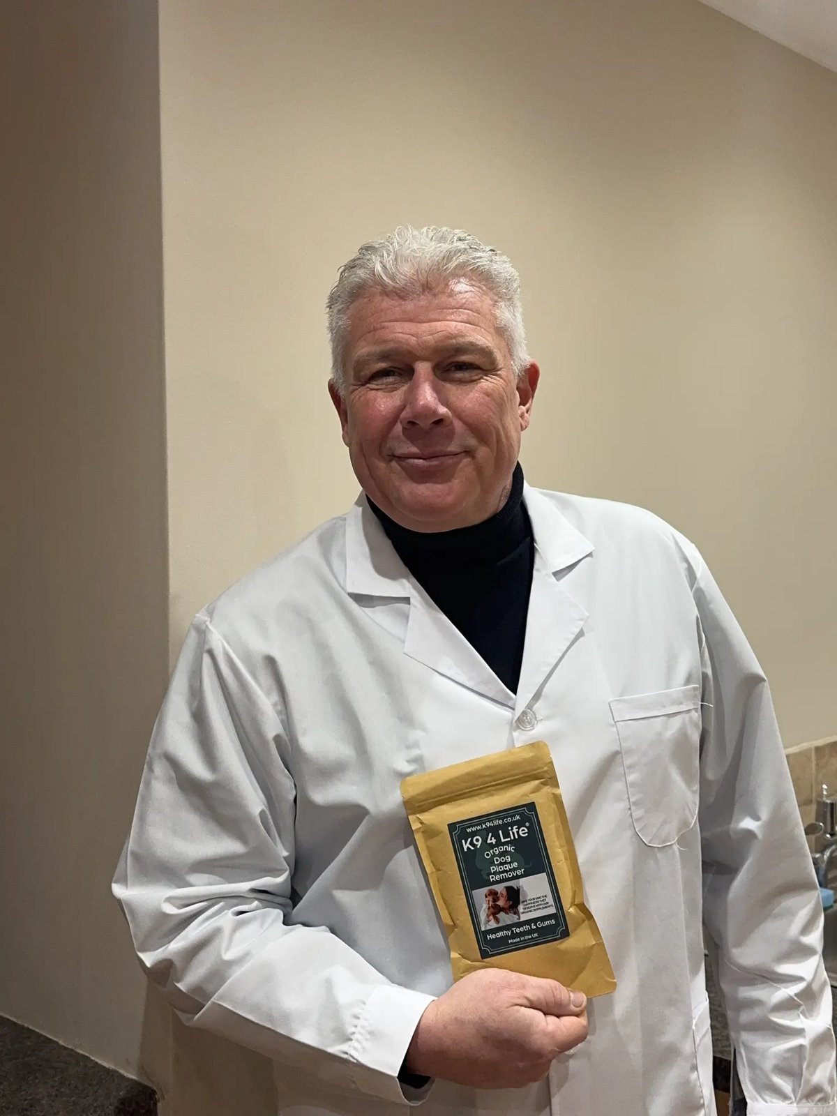 A vet in a white coat holding the K9 4 Life Organic Plaque Remover pouch.
